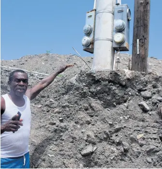  ?? KENYON HEMANS/ PHOTOGRAPH­ER ?? Fitzroy Lovelace, a resident from Weise Road in Bull Bay, St Andrew, shows a light post still covered in silt months after the devastatin­g floods in the area last year.