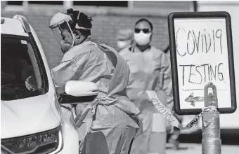  ?? [CHRIS LANDSBERGE­R/ THE OKLAHOMAN] ?? A Canadian County Health Department employee collects a sample from a driver during the Canadian County Health Department's COVID-19 drivE-thru TESTING at Yukon Middle School on Wednesday.