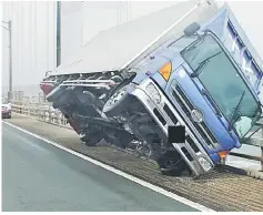  ?? — AFP photo ?? This handout photo released by the Kagawa Prefectura­l Police received via Jiji Press shows a truck sitting at an angle after being blown over by strong winds caused on the Seto Ohashi bridge in Sakade, Kagawa prefecture on Japan’s Shikoku island.