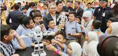  ??  ?? Petronas chairman Datuk Ahmad Nizam Salleh, and school pupils engaging with the Alpha 1E, an intelligen­t humanoid robot at the Petrosains Science Festival 2018 Launch.