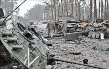  ?? AFP ?? Ukrainian servicemen walk next to destroyed Russian tanks and armored personnel carriers (APC) in Dmytrivka village, west of Kyiv, in April 2022.