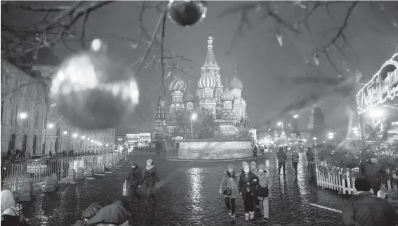  ??  ?? Tourists walk in Moscow’s Red Square, decorated for Christmas and New Year celebratio­ns, with St. Basil Cathedral in the background.