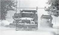  ?? DAVID ZALUBOWSKI/AP ?? Snowplows clear a Denver road Tuesday after a storm packing snow and high winds swept in. Stores, schools and government offices were closed or curtailed their hours.