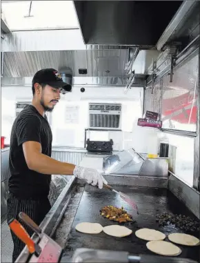  ?? Erik Verduzco ?? Las Vegas Review-journal Oswaldo Hernandez, a cook at El Buen Pastor taco truck in Las Vegas, prepares food Tuesday. Temperatur­es in the truck can reach 130 degrees in the summer.