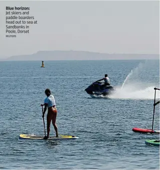  ?? REUTERS ?? Blue horizon:
Jet skiers and paddle boarders head out to sea at Sandbanks in Poole, Dorset