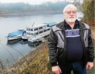  ??  ?? Peter Gerwinat vor seiner Flotte, die wegen des Niedrigpeg­els vollzählig an der Staumauer überwinter­t.Foto: Jens Voigt