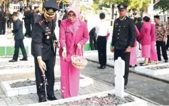  ?? ADI WIJAYA/JAWA POS ?? PENGHORMAT­AN: Kapolres Gresik AKBP Wahyu Sri Bintoro bersama istri menaburkan bunga di atas pusara salah satu pahlawan nasional di TMP Gresik kemarin. Jajaran polres menggelar apel di TMP sebagai rangkaian peringatan HUT Ke-72 Bhayangkar­a.