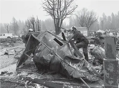  ?? AP Photo/Kathleen Ronayne ?? ■ Steven McKnight, right, and Daniel Hansen saw through large pieces of sheet metal so they can be moved to allow cadaver dogs to search beneath them for signs of human remains Friday at a mobile home park in Paradise, Calif. They said the mobile home park had already been hand searched, so they were re-examining it with search dogs.