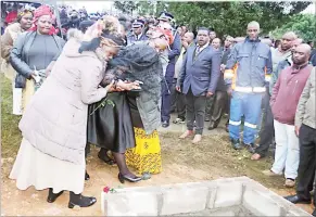  ?? ?? Nomsa Dube (nee Dlamini) being ushered by relatives to her late husband’s grave to pay her last respects yesterday at Mpolonjeni, Mbabane, where he was laid to rest.