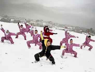  ?? — AP ?? Positive vibes: Shaolin martial arts students following their trainer, Sima Azimi, 20, in black, during a training session on a hilltop in Kabul, Afghanista­n.