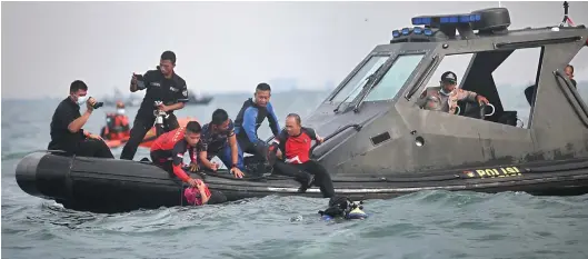 ?? DEMY SANJAYA/AFP ?? DARI DALAM LAUT: Para penyelam membawa berbagai serpihan badan pesawat yang ditemukan di perairan Kepulauan Seribu kemarin.
