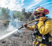  ?? /AFP ?? Scorched earth: Santa Fe Springs firefighte­rs hose down the embers of one of the wildfires that are ravaging California.