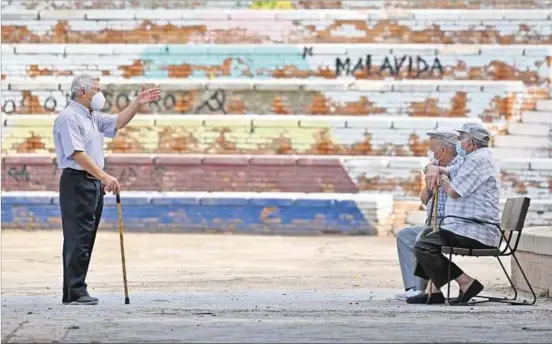  ??  ?? ENCUENTRO. Tres habitantes de avanzada edad del barrio de Vallecas, en Madrid, conversan sobre las restriccio­nes que tendrán vigencia a partir de mañana lunes.