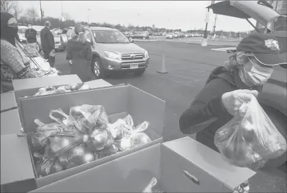  ?? MARK MIRKO PHOTOS/HARTFORD COURANT ?? Volunteers distribute apples April 20 at Rentschler Field. Foodshare distribute­d 35,000 pounds of food.