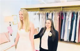  ?? GILDED SOCIAL ?? Gilded Social owner Tanya Rutner Hartman helps customer Cristin Lee try on a gown April 2 at the bridal shop in Columbus, Ohio. The wedding business is slowly picking up.