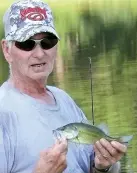  ?? Staff photo by Neil Abeles ?? This little fellow is too small, R.K. Tilley said, so he’ll throw the fish back in to be caught another day at Queen City Independen­t School District pond.