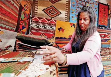  ?? [PHOTOS BY STEVE SISNEY, THE OKLAHOMAN] ?? Lucy Mendez puts out hand-loomed rugs during the Festival of the Arts.