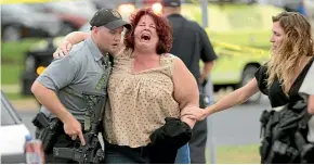  ?? AP ?? A woman is escorted from the scene of a shooting at a software company in Middleton, Wisconsin, where three people were shot and wounded and a gunman killed by police.