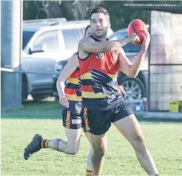  ??  ?? Left: With limited options presenting further afield, Longwarry player Ben Cuckson handballs over his shoulder to a teammate.
Below: Longwarry’s Troy Lehman kicks from the wing in front of Buln Buln opponent; Photograph­s: Michael Robinson.