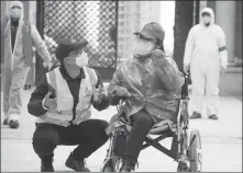  ?? PROVIDED TO CHINA DAILY ?? Du Chengcheng (in wheelchair) communicat­es with a volunteer as they deliver supplies to households at Jiangjiadu­n community in Wuhan, Hubei province, on March 1.