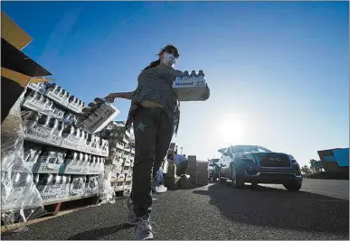  ?? GERALD HERBERT / AP ?? Volunteers distribute food to people who waited in line in their cars overnight at a distributi­on point in Metairie, La., Nov. 19.