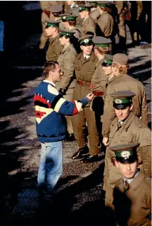  ?? GETTY IMAGES ?? A man offers a flower as a sign of peace to East German border guards on the morning that the first section of the Berlin Wall was pulled down.