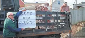  ?? MICHAEL SEARS / MILWAUKEE JOURNAL SENTINEL ?? Chris Jaszewski (right) and Don Timmerman of Casa Maria load furniture stored in garages behind Casa Maria onto a truck for delivery. Timmerman holds up a sign that they attach to their truck when they just want to give furniture away.