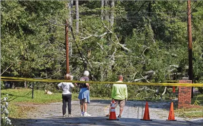  ?? HYOSUB SHIN / HSHIN@AJC.COM ?? Residents watch over a huge fallen tree that knocked out power to their Tucker neighborho­od on Wednesday. About 480,000 Georgia homes and businesses remained without power, two days after Tropical Storm Irma hit the state.