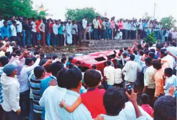  ?? PTI ?? People surround the car carrying three of the young men who came under attack from a crowd in Karnatak’s Bidar district. A 22-year-old software engineer was killed in the incident.