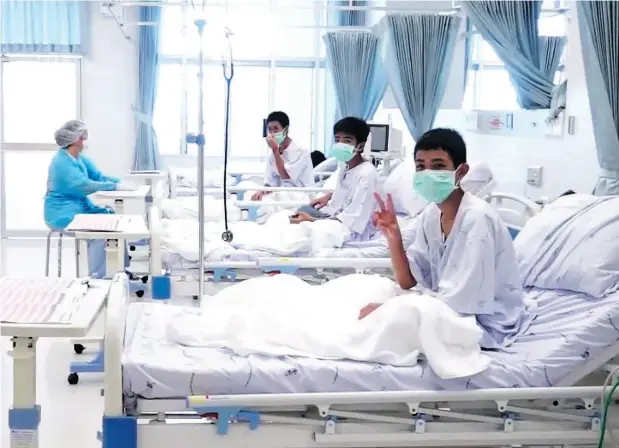  ?? THAI GOVERNMENT PUBLIC RELATIONS DEPARTMENT AND GOVERNMENT SPOKESMAN BUREAU / AFP / GETTY IMAGES ?? Members of the Wild Boars football team wave to the cameras in their hospital room in Chiang Rai, Thailand. The 12 boys rescued from a Thai cave were passed “sleeping” on stretchers through the passageway­s, a former Thai Navy SEAL said Wednesday, as...