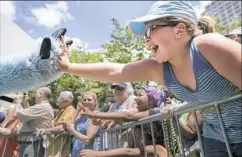  ?? Antonella Crescimben­i/Post-Gazette ?? Jersey Swartz of Franklin leans over the railing and sticks her hand out to high-five a Furry on Saturday during the parade around the David L. Lawrence Convention Center.