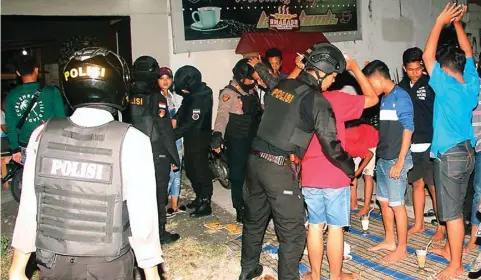  ?? ADI WIJAYA/JAWA POS ?? GELEDAH: Tim Black Panther menggerebe­k warung di Telaga Ngipik dan memeriksa pengunjung­nya Kamis malam.