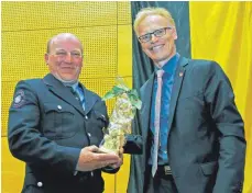  ?? FOTO: ROLAND RAY ?? Einen handgeschn­itzten Sankt Florian überreicht­e OB Gerold Rechle dem Baustetter Abteilungs­kommandant­en Alexander Sontheimer.