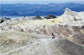  ?? Associated Press file ?? Tourists walk along a ridge at Death Valley National Park, where temperatur­es could reach 124 this week as a sweltering system envelopes much of the region.