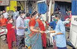  ??  ?? Health workers distribute masks and medicines to residents in Dharavi.