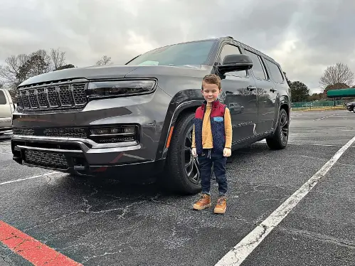  ?? It to the maker. (Photo by James Bright) ?? Jackson Bright, son of James Bright who reviews the Jeep Grand Wagoneer, stands next to the vehicle before returning