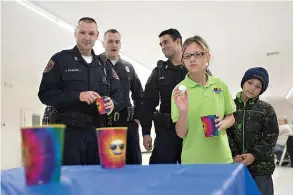  ?? Staff photo by Evan Lewis ?? n Karolina, 12, plays table pong as Texarkana, Ark., police Officers Kelly Pilgreen, Brian Tribble and T.J. Miles look on Thursday. TAPD partnered with the Texarkana, Ark., Citizens Police Academy Alumni Associatio­n to treat the children from...