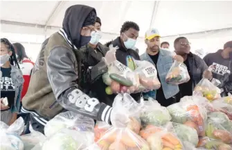  ?? PAT NABONG/SUN-TIMES PHOTOS ?? Comedian and rapper Nick Cannon (left) and rapper G Herbo (second from left) on Saturday during a food drive in the parking lot of the Pullman Community Center.