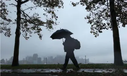  ?? ?? A person walks in the rain during the nor’easter in Hoboken, New Jersey, on 26 October. Photograph: Gary Hershorn/Getty Images