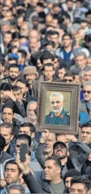  ??  ?? Protesters hold up an image of slain Iranian commander Qassem Soleimani during a rally in Tehran. BLOOMBERG