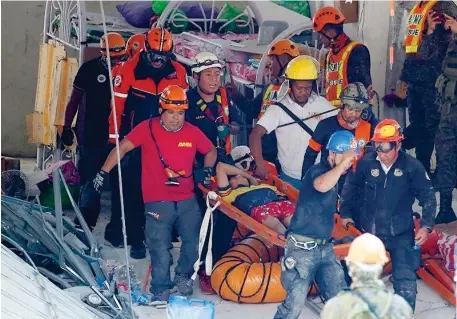 ?? (AP Photo) ?? PAMPANGA. Rescuers carry an earthquake survivor after being pulled out from the rubble of a commercial building following a 6.1 magnitude earthquake in Porac township, Pampanga province, north of Manila, Philippine­s, Tuesday, April 23, 2019. The strong earthquake struck the northern Philippine­s Monday trapping some people in a collapsed building, damaged an airport terminal and knocked out power in at least one province, officials said.