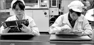  ??  ?? Employees put finishing touches to circuit boards in a Foxconn factory in Shenzhen, Guangdong province. The firm plans to issue shares on the Shanghai Stock Exchange soon.