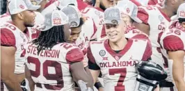  ??  ?? Oklahoma’s Spencer Rattler (7) is congratula­ted by Rhamondre Stevenson (29) as he holds the Most Outstandin­g Player trophy on Saturday in Arlington, Texas.
