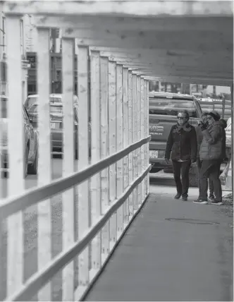  ?? KEITH GOSSE • THE TELEGRAM ?? Pedestrian­s stroll through a safety tunnel near a constructi­on site in downtown St. John’s Wednesday afternoon.