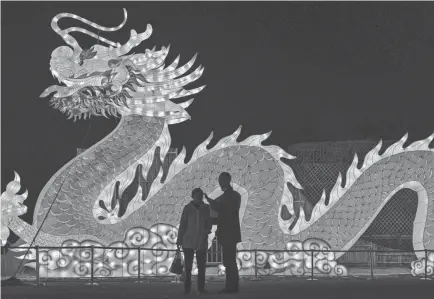  ?? HECTOR RETAMAL/AFP VIA GETTY IMAGES ?? People talk in front of a giant dragon lantern in a park in Wuhan in China’s central Hubei province Thursday, ahead of the start of the Lunar New Year on Friday.