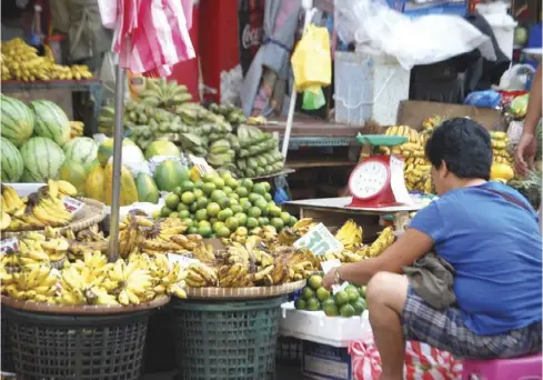  ?? AP ?? A fruit vendor is seen looking after her stall at a busy market in Metro Manila.
