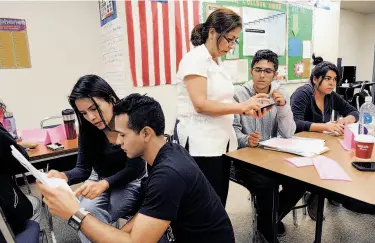  ?? Photos by Michael Short / The Chronicle ?? Katty Rojas and Eduardo Sagrero look over their work (left) as teacher Nooshin Vassei (center) helps Farbod Safaei during a writing class at the Sequoia District Adult School in Menlo Park.
