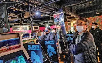  ??  ?? Staff member (centre) speaking as he presents a video game fighting match at the Mikado game centre in the Shinjuku district of Tokyo.