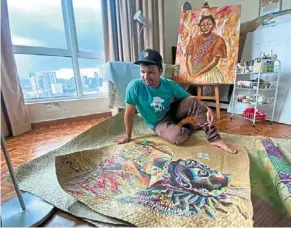  ?? ?? shaq Koyok rolls out a portrait painted on a mengkuang mat, an art style that has reconnecte­d him with his Orang asli roots. — bernama