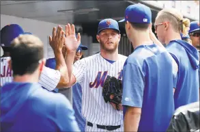 ?? Jim McIsaac / Getty Images ?? Zack Wheeler of the New York Mets is greeted in the dugout by his teammates after leaving a game against the Detroit Tigers in the eighth inning at Citi Field on Sunday in New York. The Mets won 4-3.